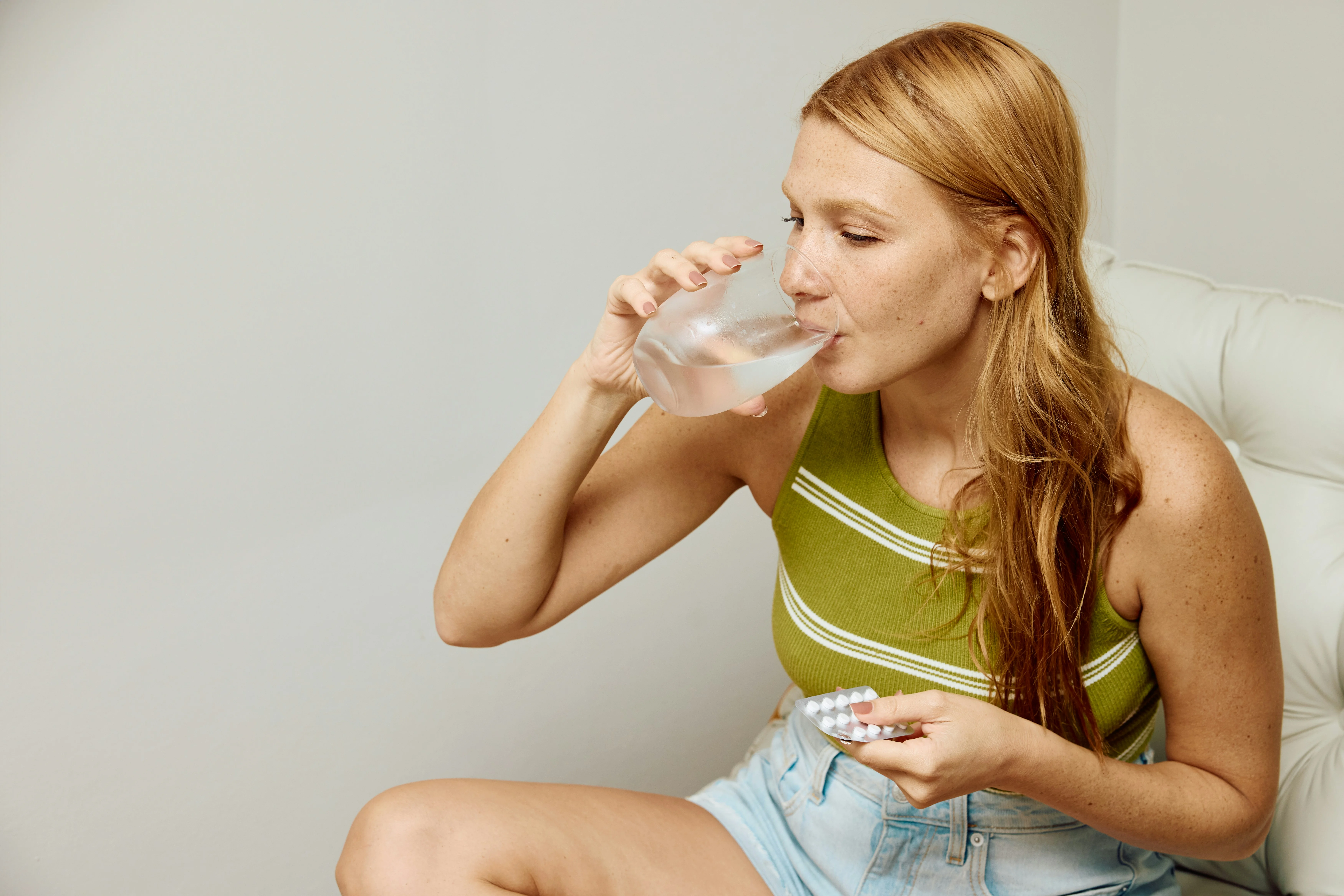woman drinking water and holding pills